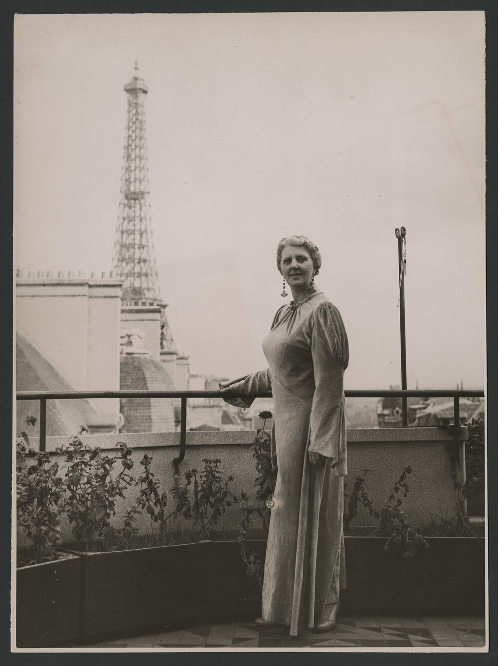 Louise Dyer in  floor-length gown with the Eiffel Tower visible in the background