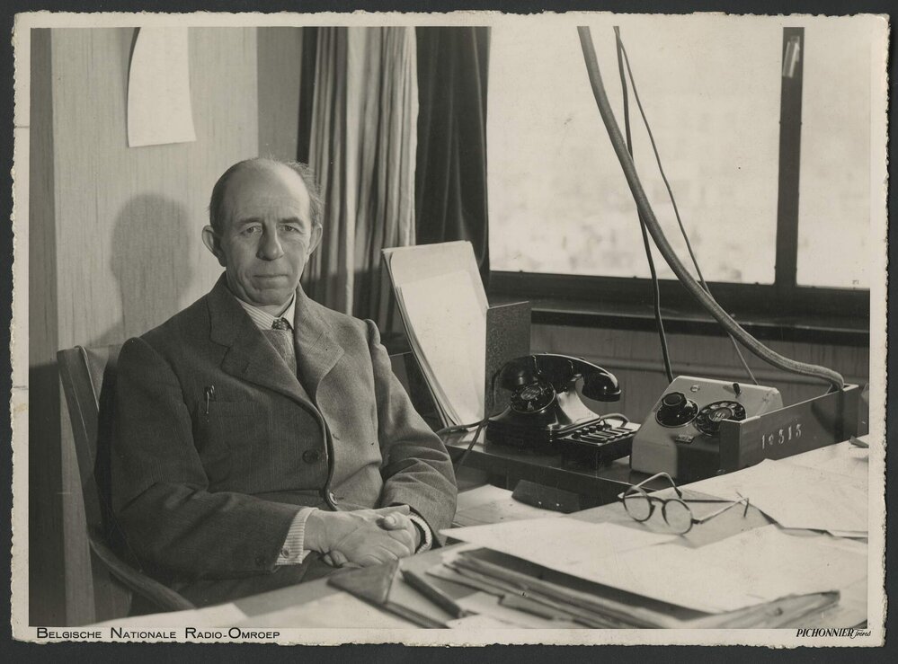 Musicologist Paul Collaer seated at his desk at the Belgian National Radio