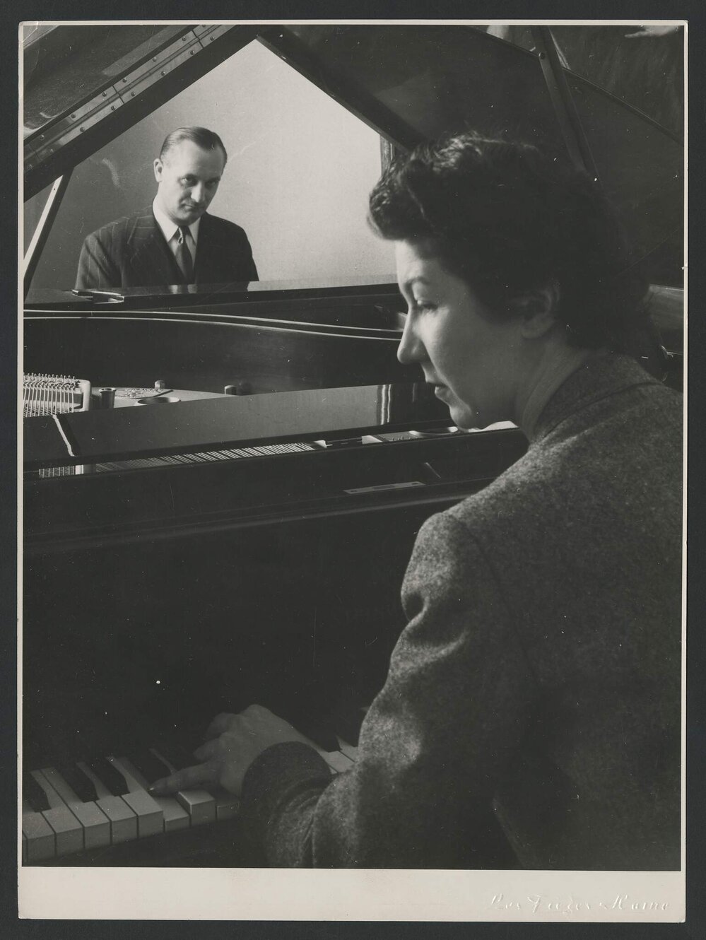 Unknown man sitting opposite Isabelle Nef at the piano, who is visible in side profile