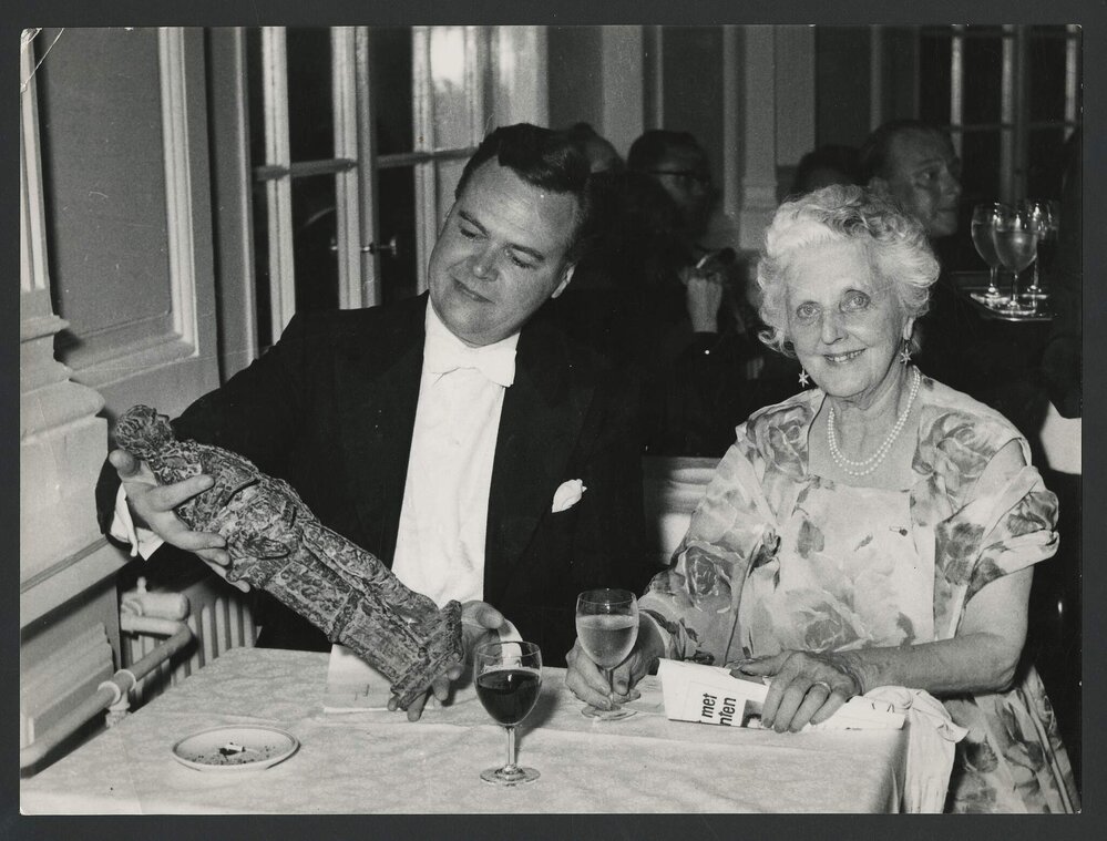 Thurston Dart holding the Grand Prix du Disque award seated next to an elderly Louise Hanson-Dyer