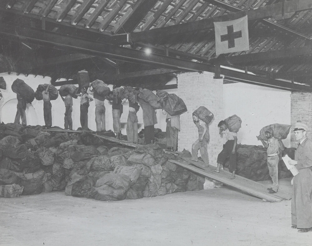 Men carrying Red Cross parcels in single file