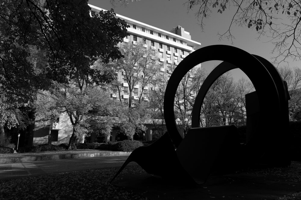 Parkville during COVID lockdown - Inge King Sun Ribbon Sculpture located on University Plaza with Raymond Priestley Building in background - Monochrome