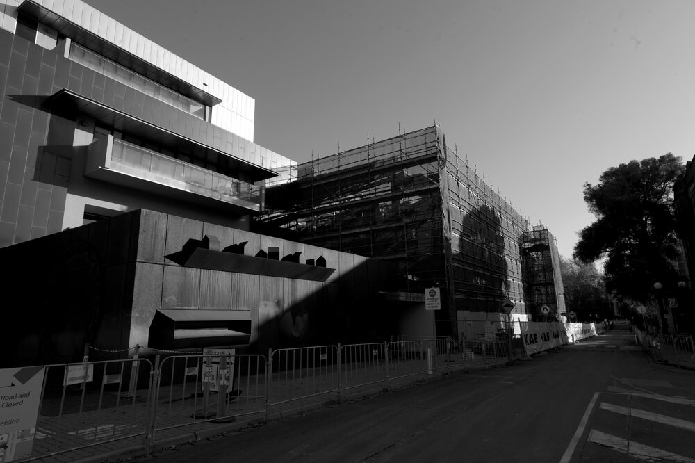 Parkville during COVID lockdown - New Student Precinct Construction site photographed from corner of Swanst St and Monash Rd with Sidney Myer Asia Centre in foreground - Monochrome