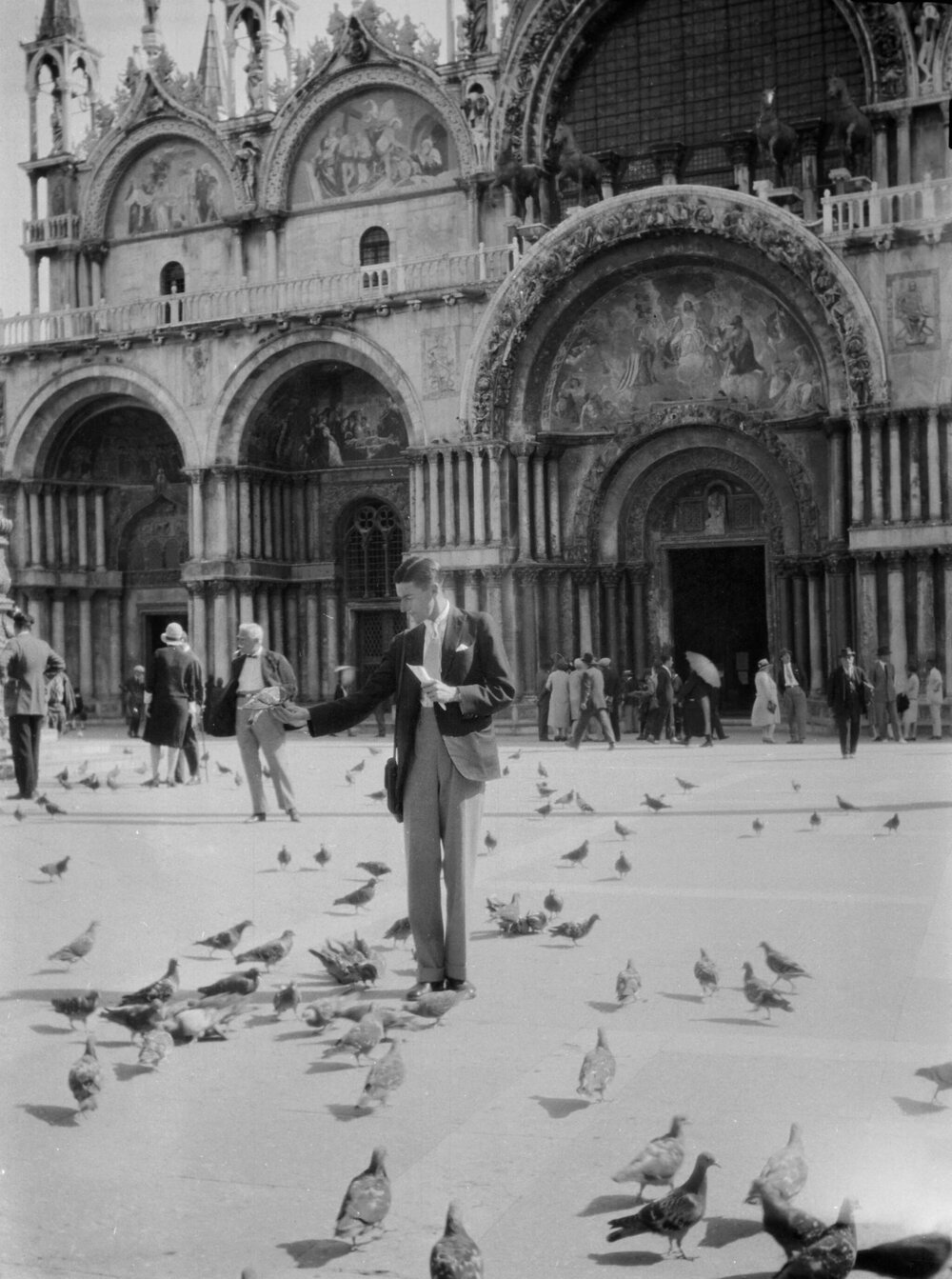 A unidentified young man feeding pigeons in St Mark's Square Venice, Italy