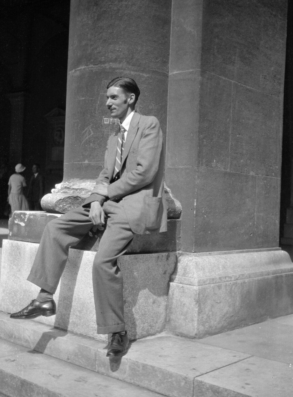An unidentified man seated at the base of a building column in Vienna, Austria