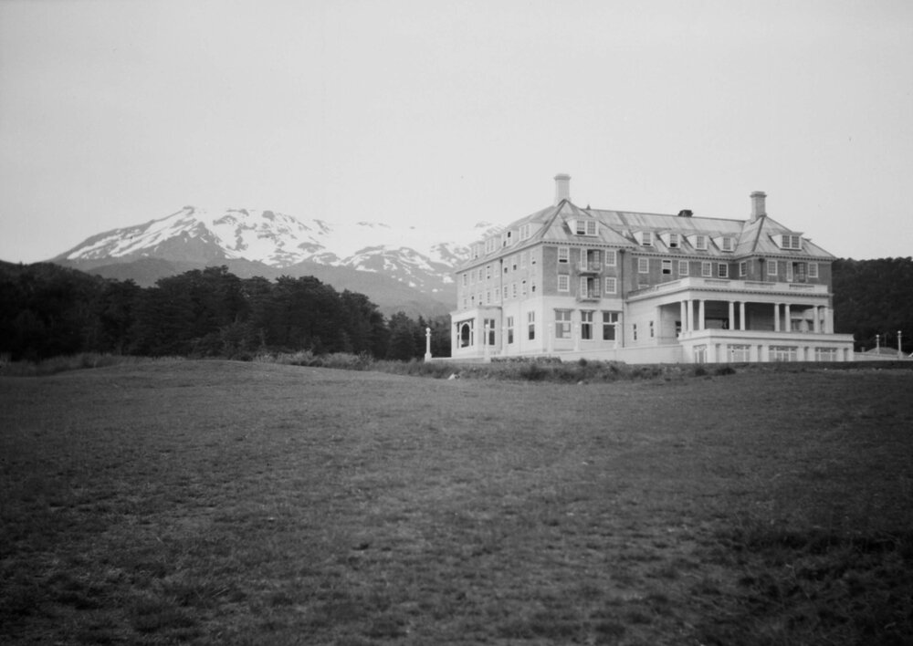 A large house, mansion or hotel and a snow covered mountain at an unknown location in New Zealand