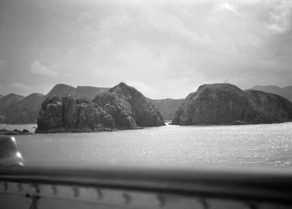 A view from the deck of a ship of islands and coastline at an unidentified location in New Zealand