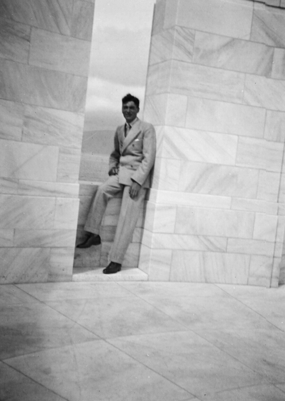 An unidentified man standing at (possibly) a war memorial at an unknown location in New Zealand
