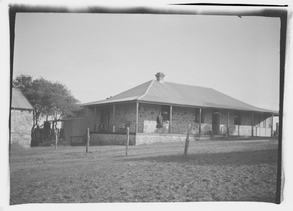 An unidentified woman and young girl on the verandah of a stone farmhouse