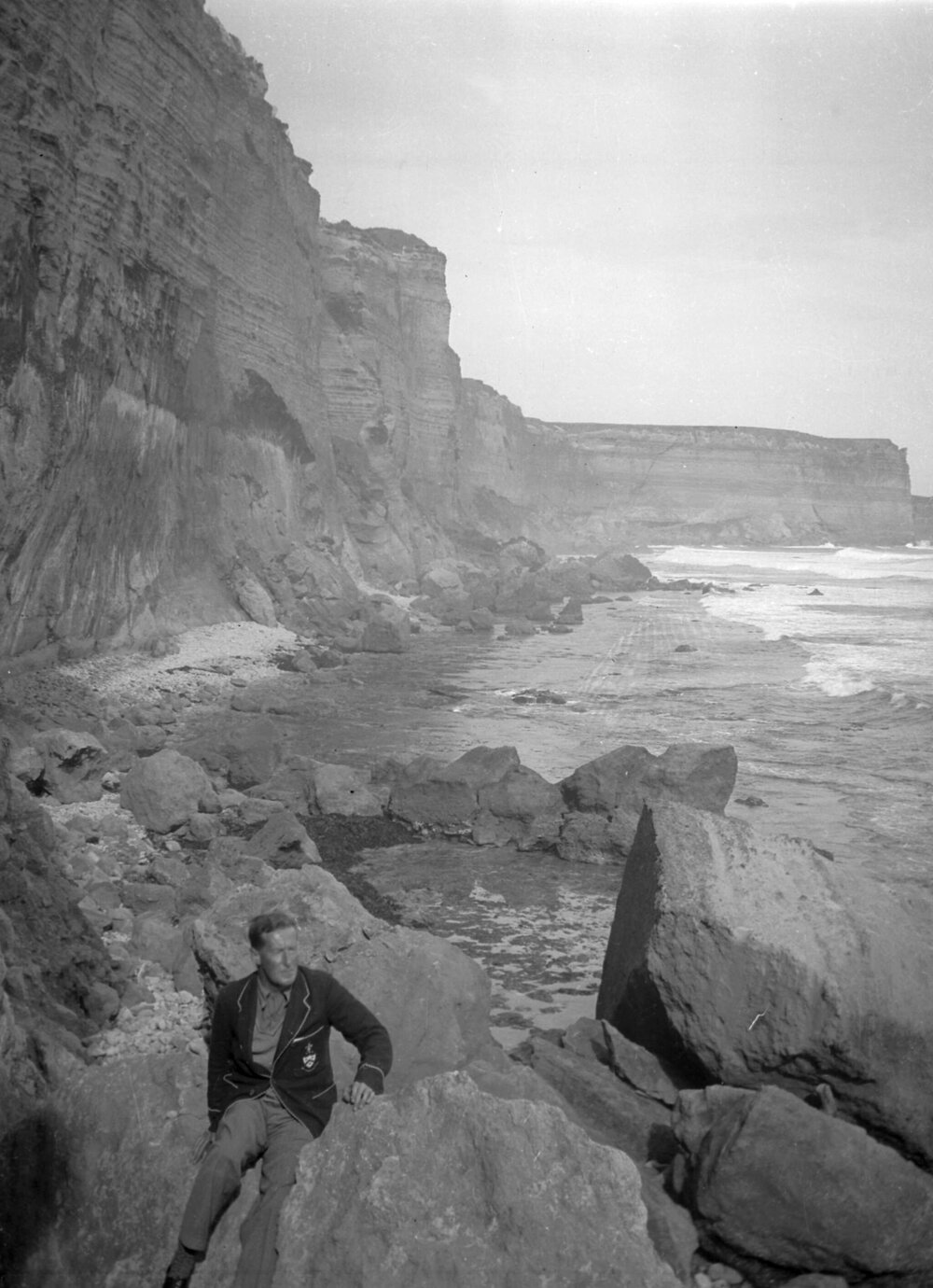 An unidentified man seated on rocks at or near Port Campbell, Victoria