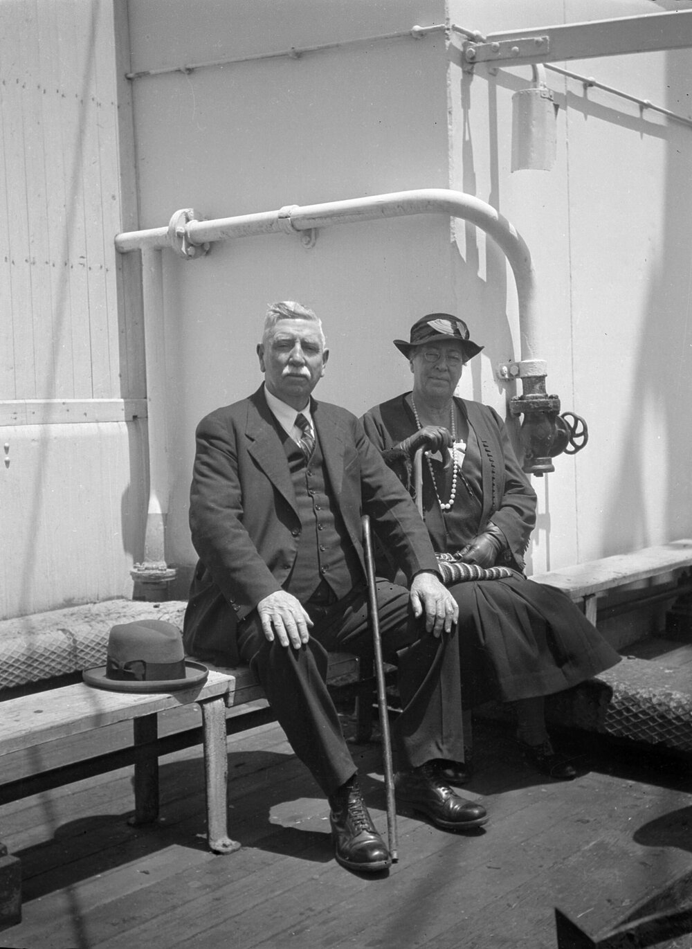 An elderly man and woman seated on the deck of a ship [they appear to be the parents of Charles E