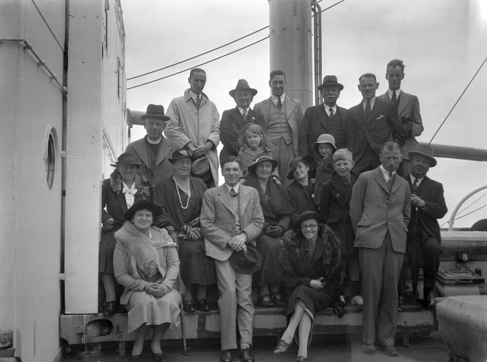 A posed group of nineteen people on the deck of a ship