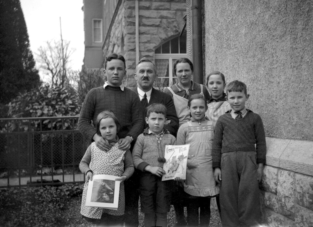 An unidentified family group of a woman, man and six children posed outside a building