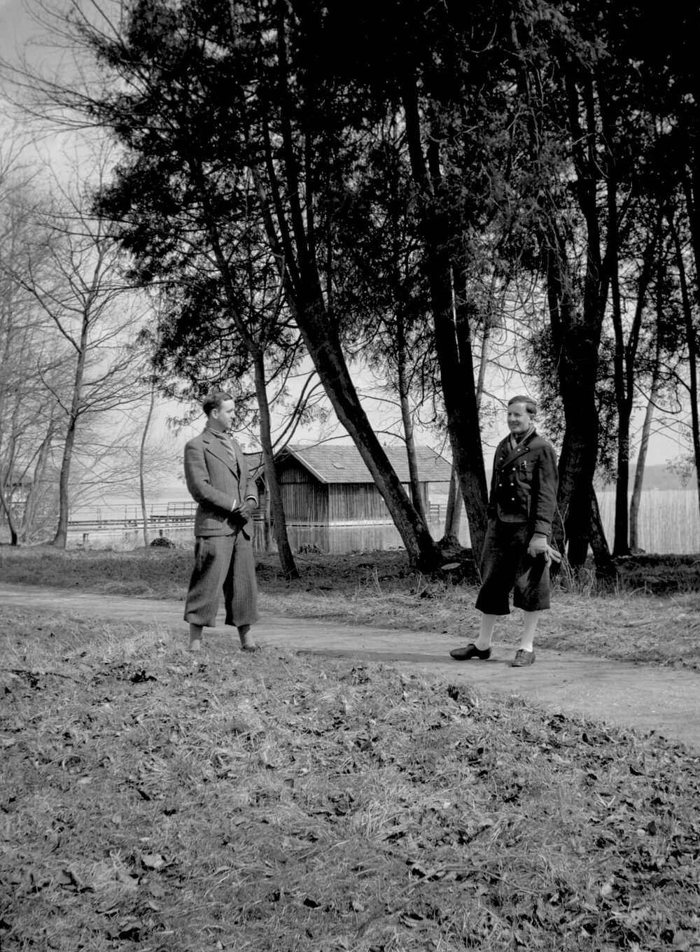 Two unidentified well-dressed men on the shore of a lake at an unknown location