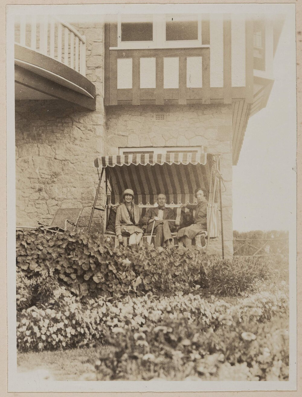 [Daryl and Joan Lindsay and Mab sitting on outdoor swing chair at Westerfield]