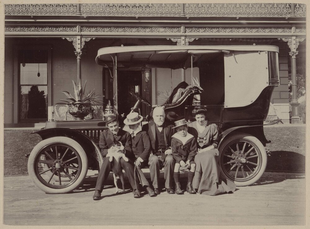 Grimwade family members seated on the running board of a motor car at Harleston