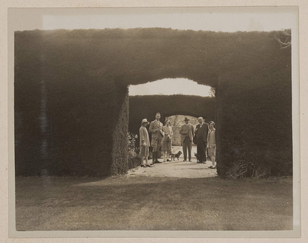 [Group of people and dogs posed next to hedge arch,] Ercildoune [Homestead]