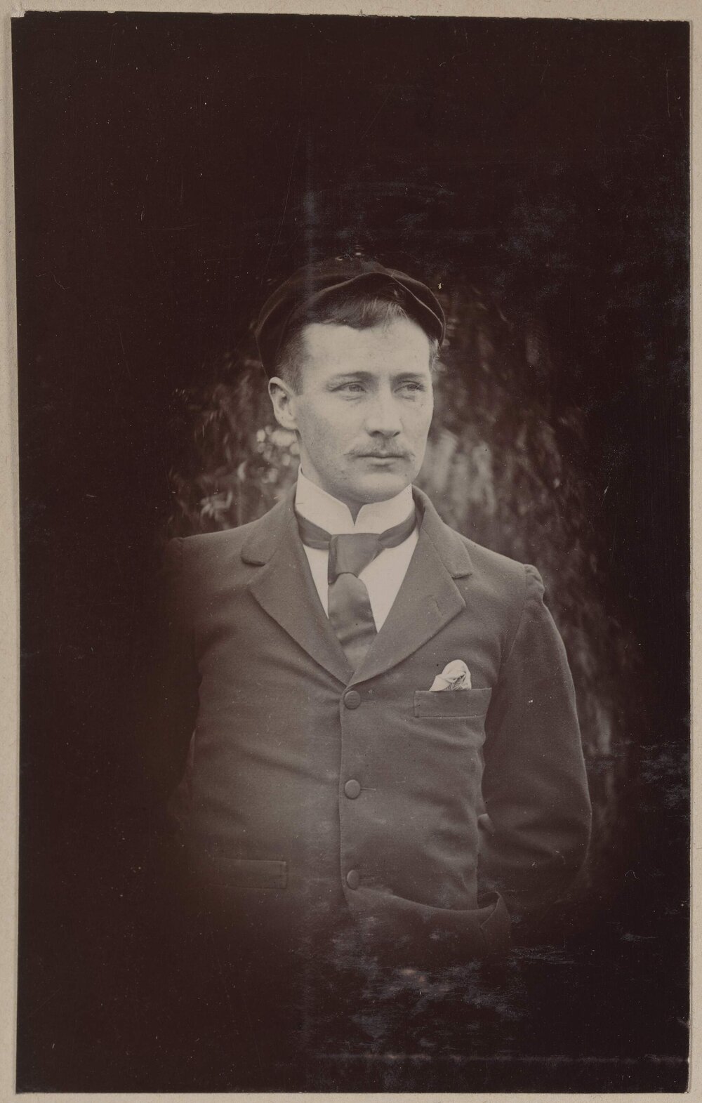 [Man with moustache wearing cap, jacket and tie]