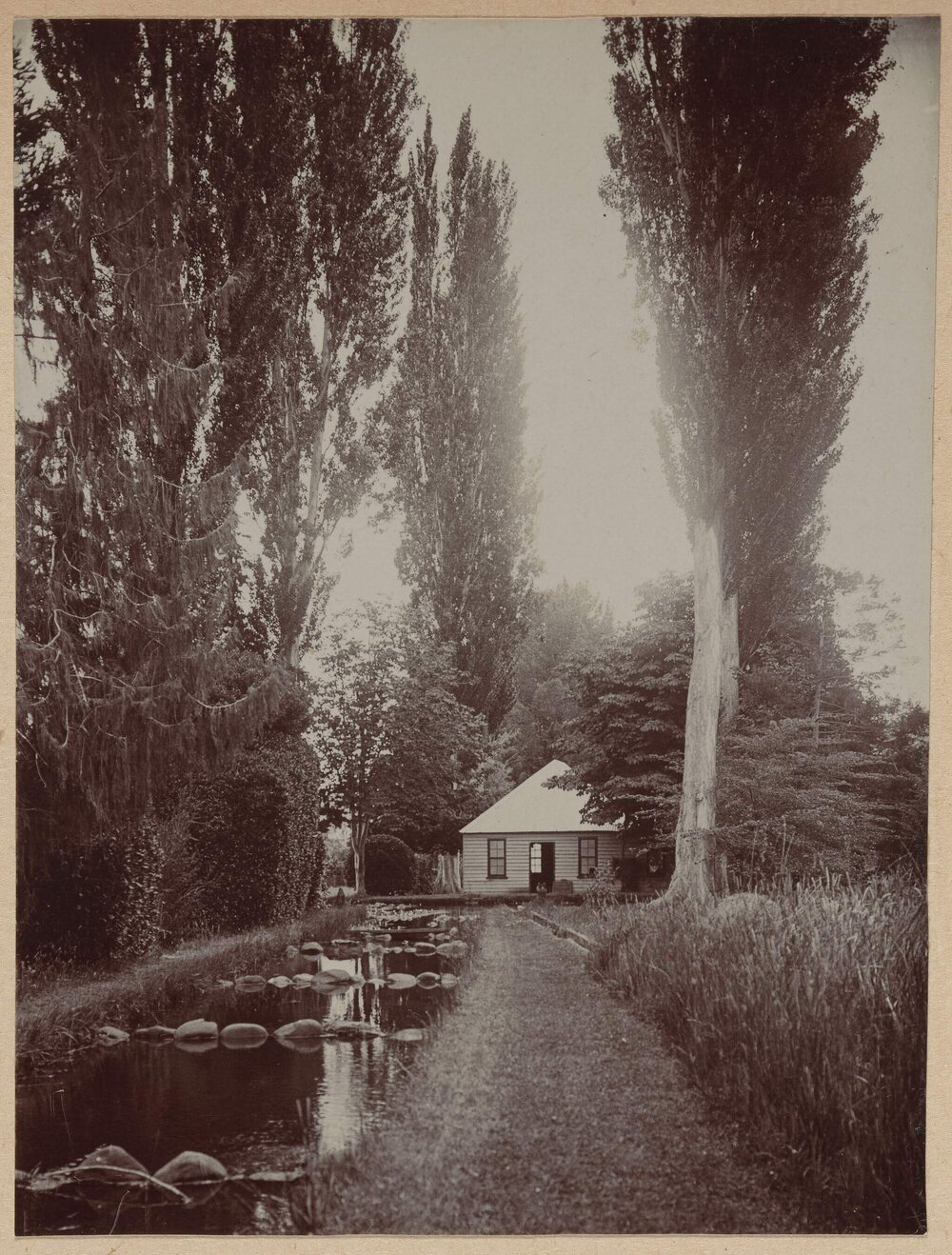 [Wooden house next to rectangular pond]