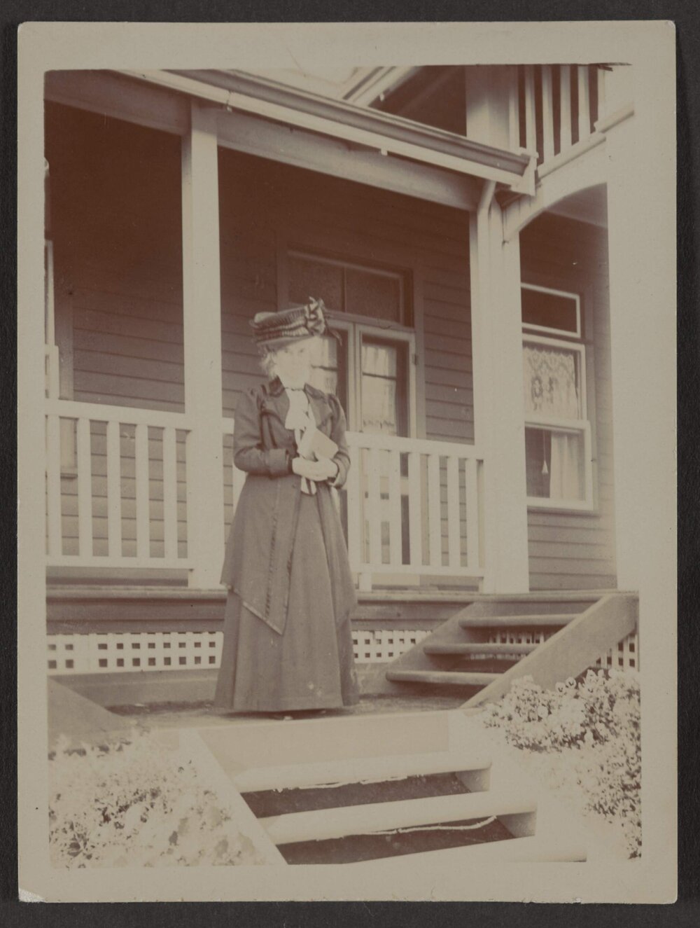 [Woman standing outside house]