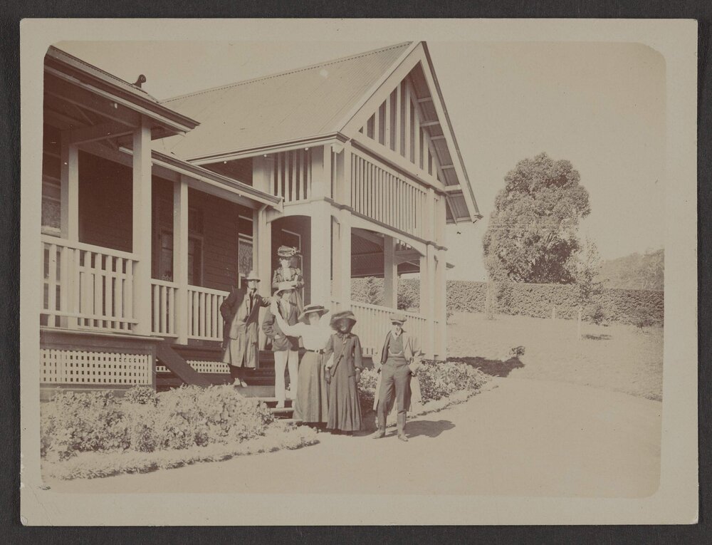 [Group photo, men and women in front of house]