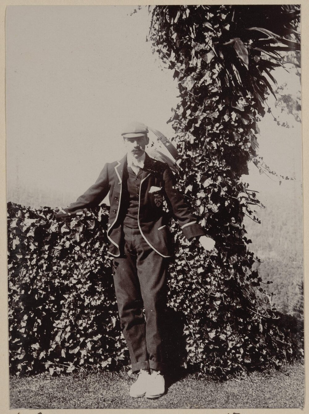 [Man posing in front of hedge]