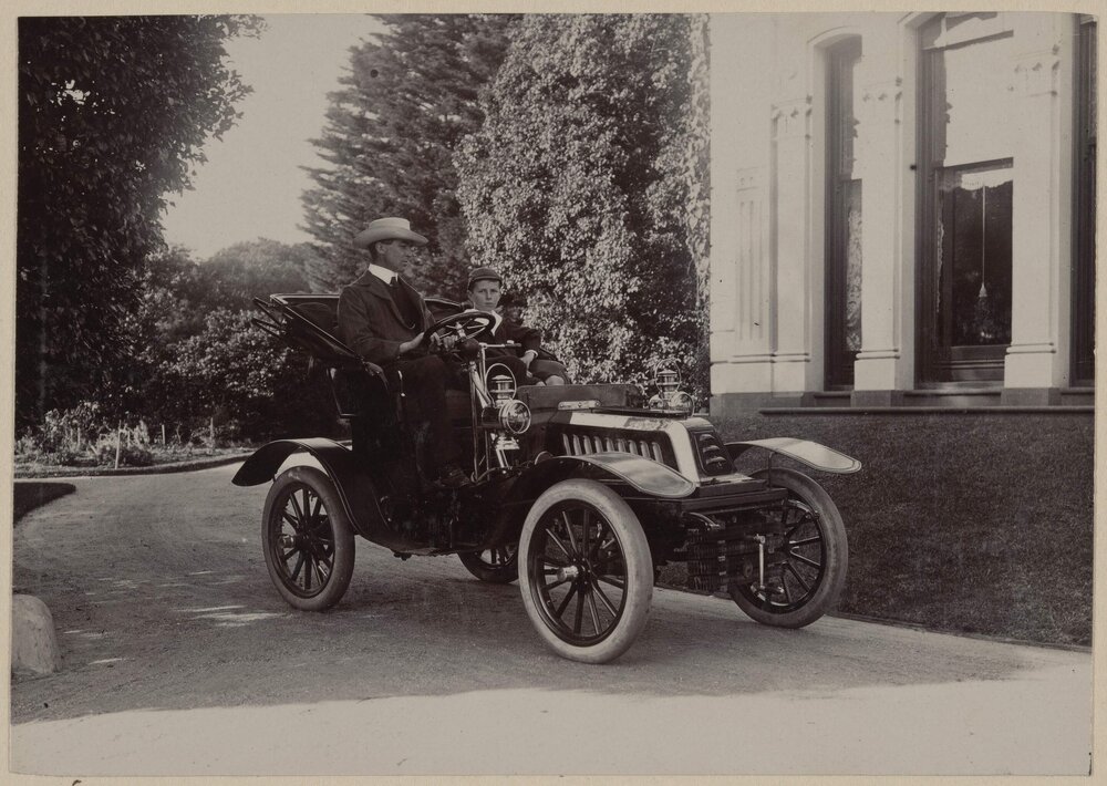 [Man and boy seated in motor car]