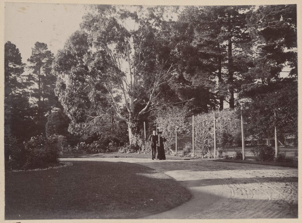 [Man and woman walking on garden pathway]
