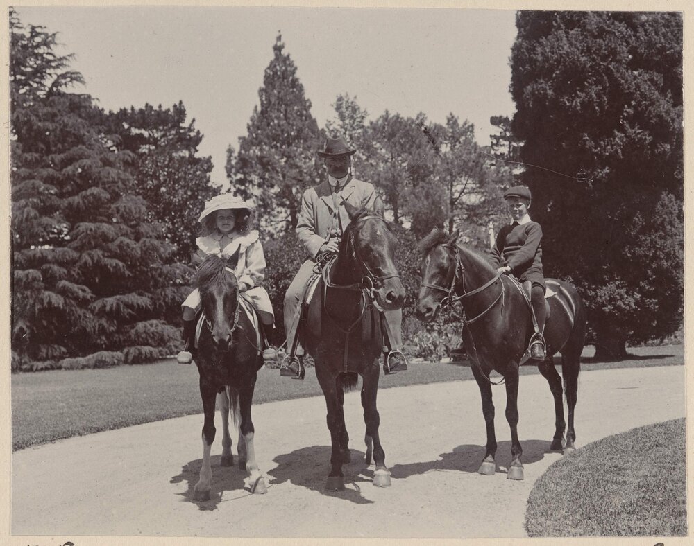 [A man and two children on mounted on horses]