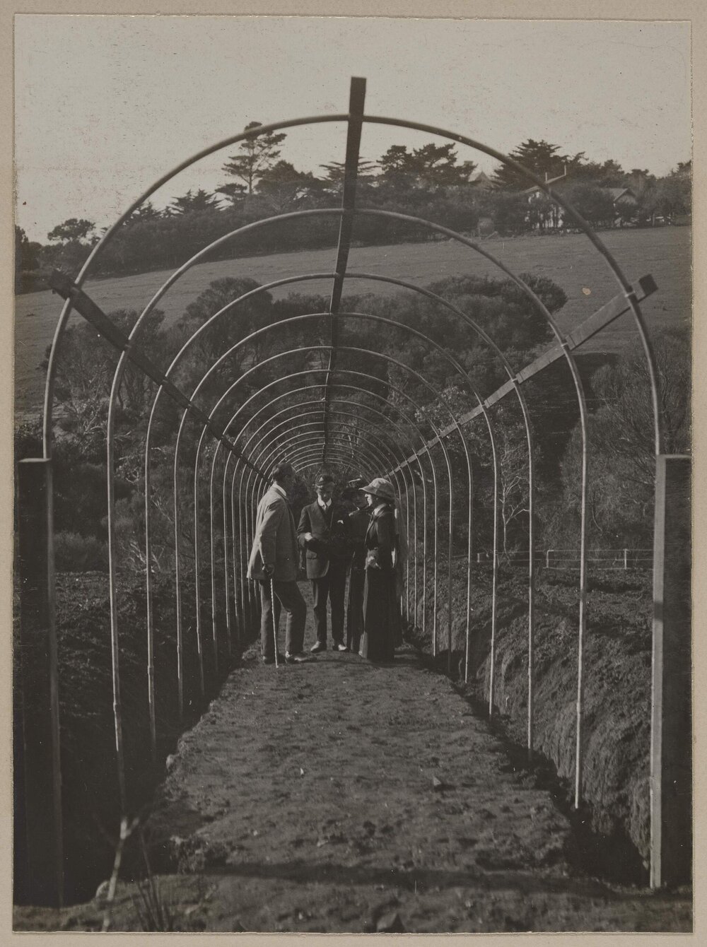 [Group standing under garden arch trellis]
