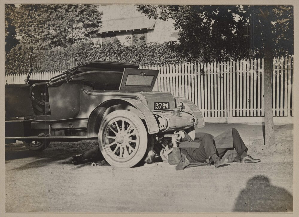 [Man laying under motor vehicle]