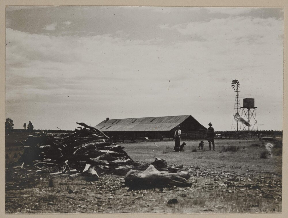 [Man and woman in front of farm shed]