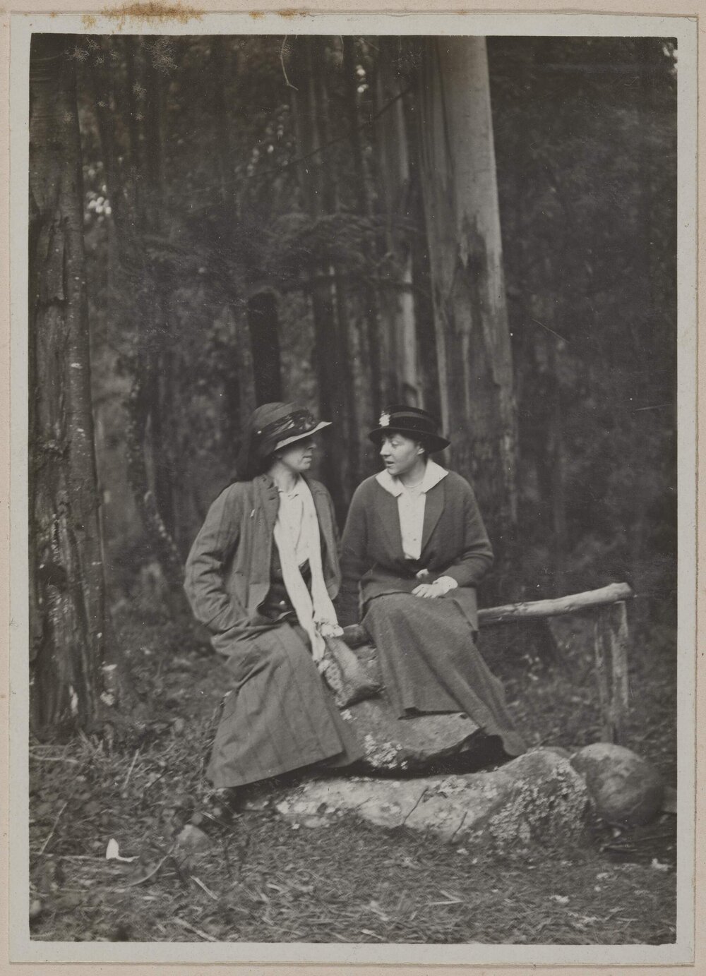[Two women in seated pose in forest]