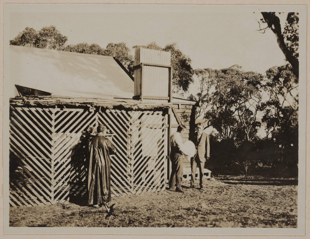 [Three men standing behind house]