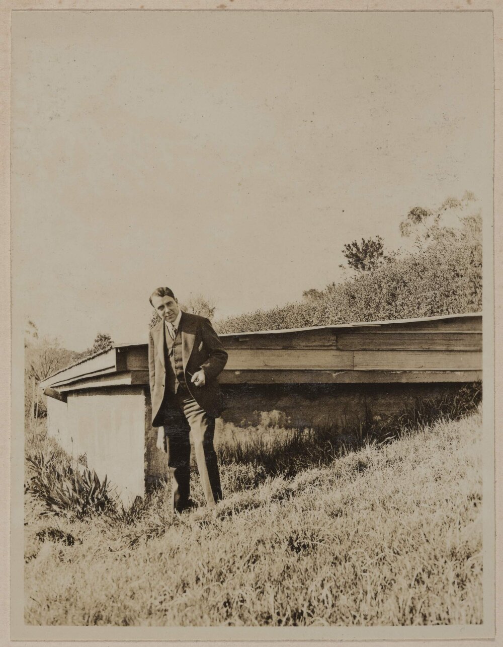 [Man posing next to wooden structure]