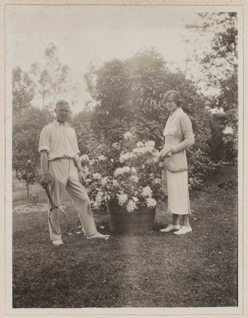 [Man and woman posed next to large flower pot]