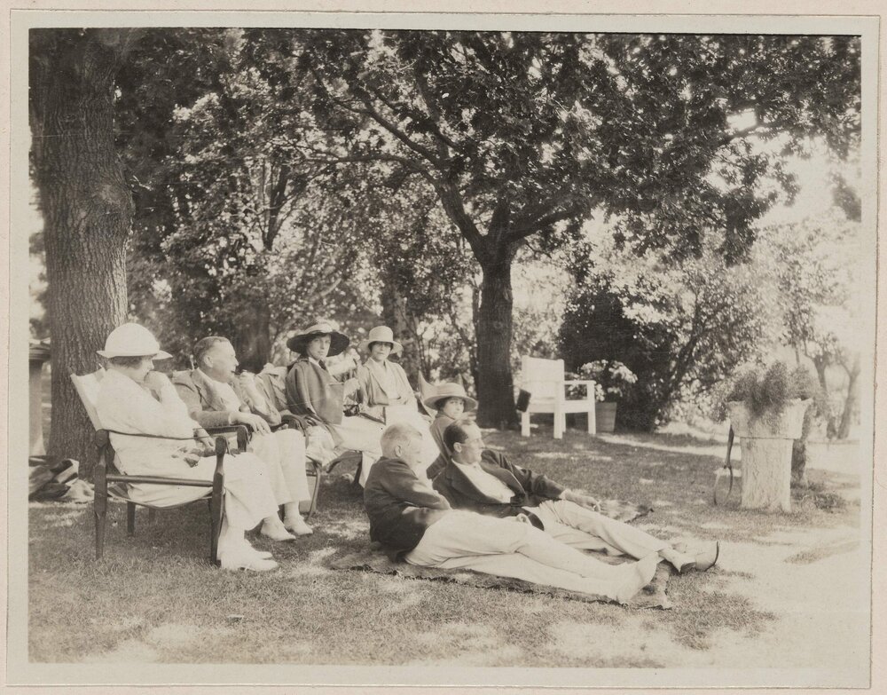 [Group of men and women seated together in garden]
