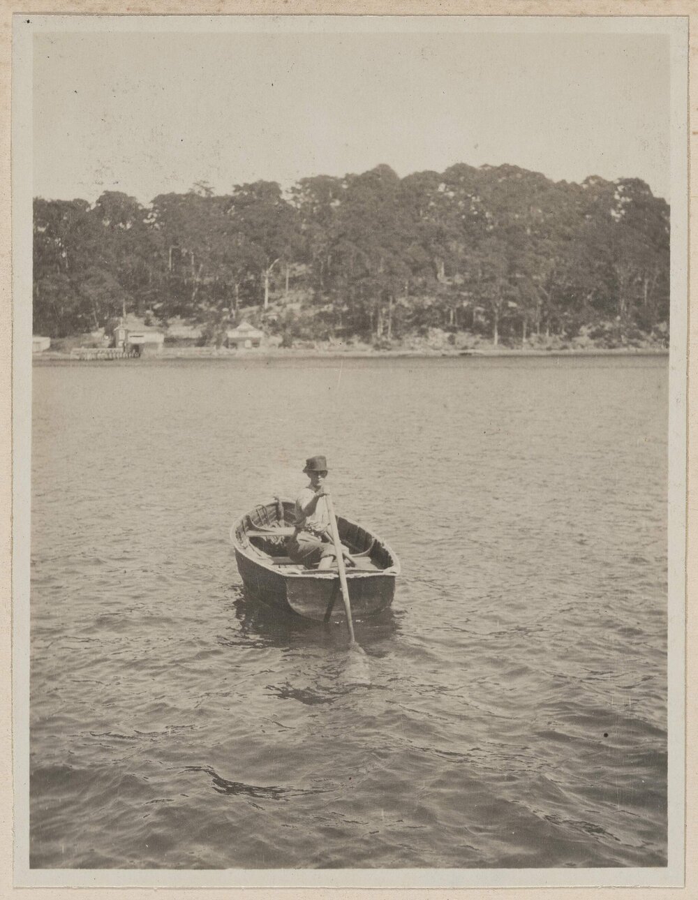 [Woman in row boat holding single oar]