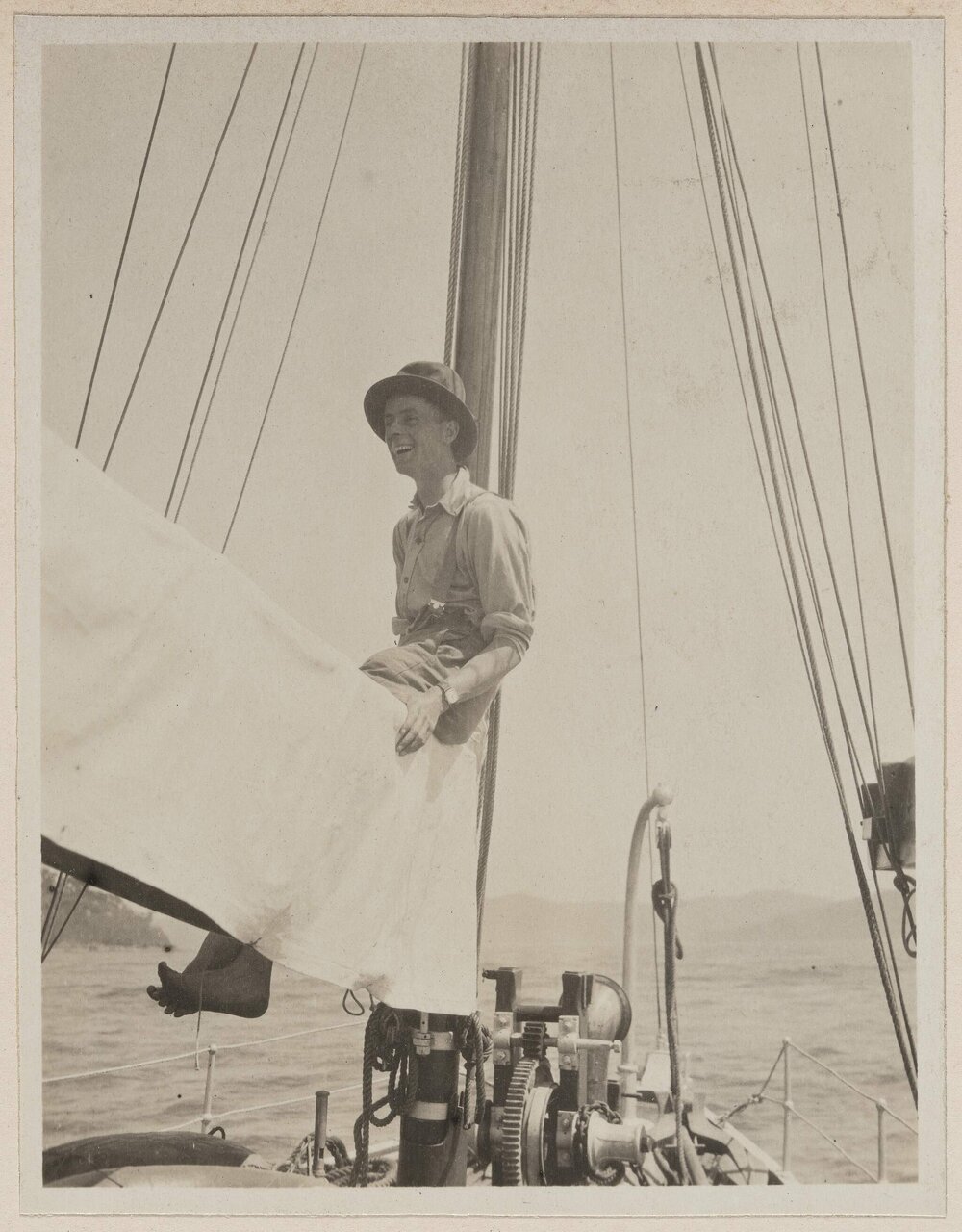 [Man sitting on sail boom on yacht]