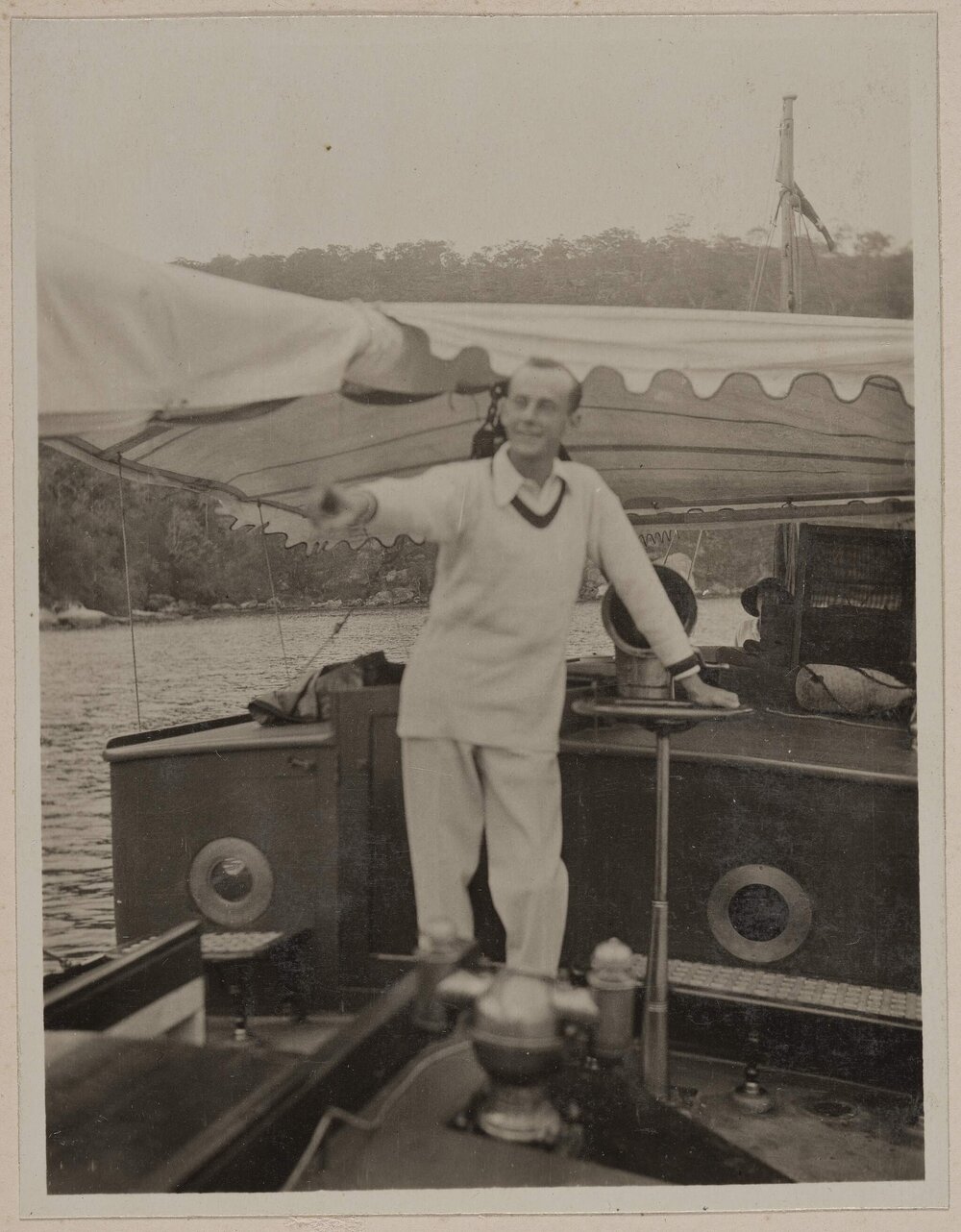 [Man pointing, standing on deck of yacht]