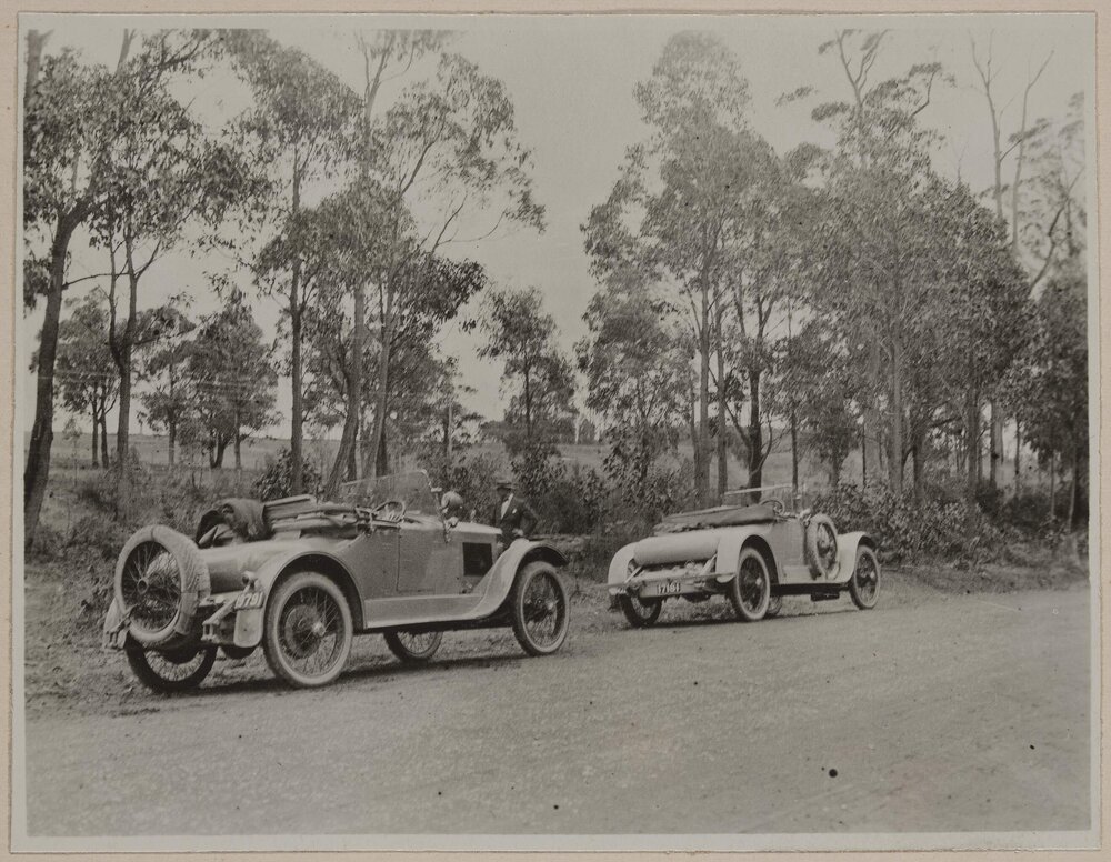 [Two motor cars parked on road]