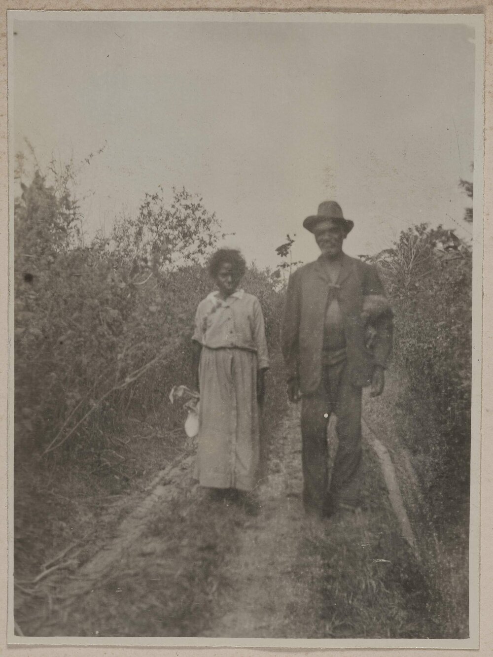 [Young girl and man standing in field]