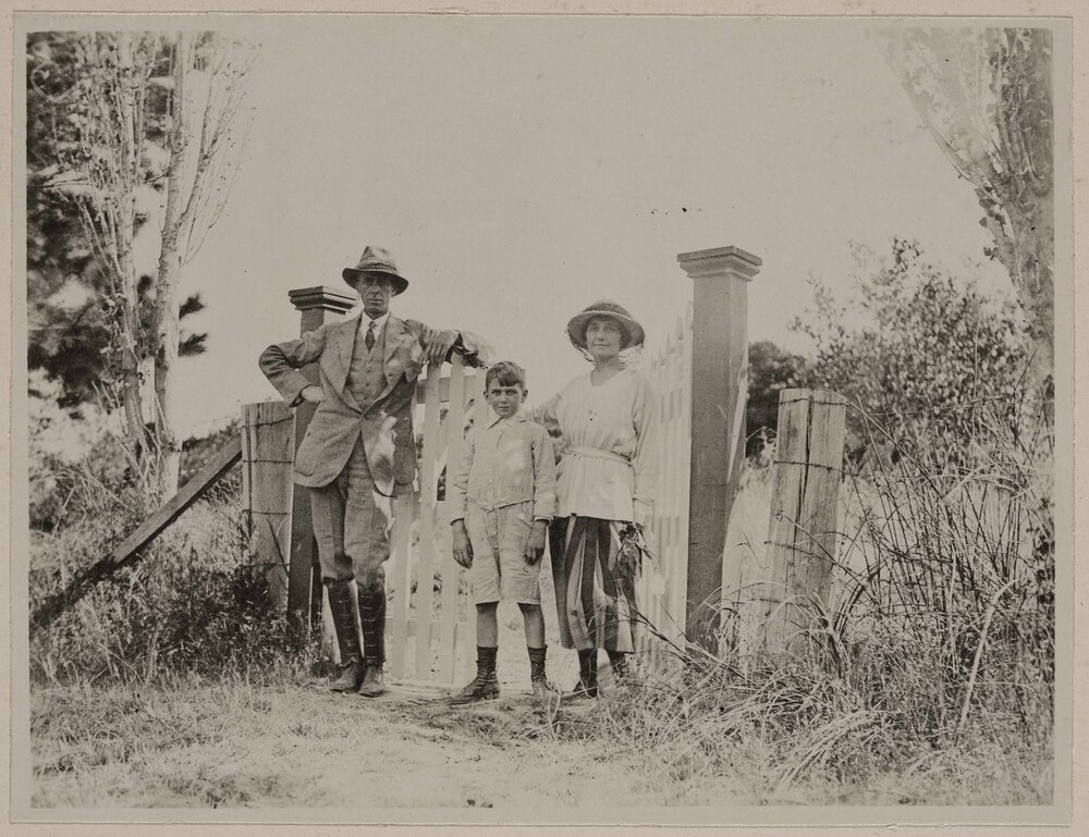 [Man and woman with young boy posing at property gate]