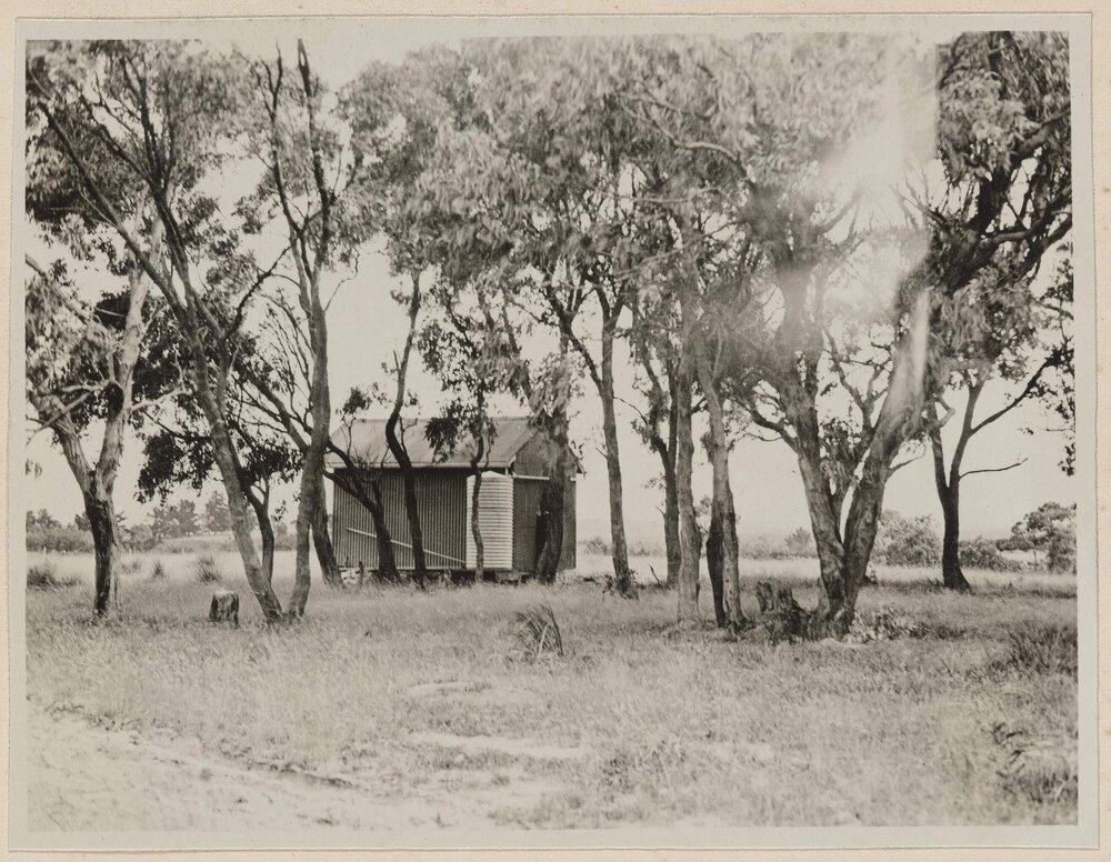 [Exterior of small outbuilding with chimney and water tank]