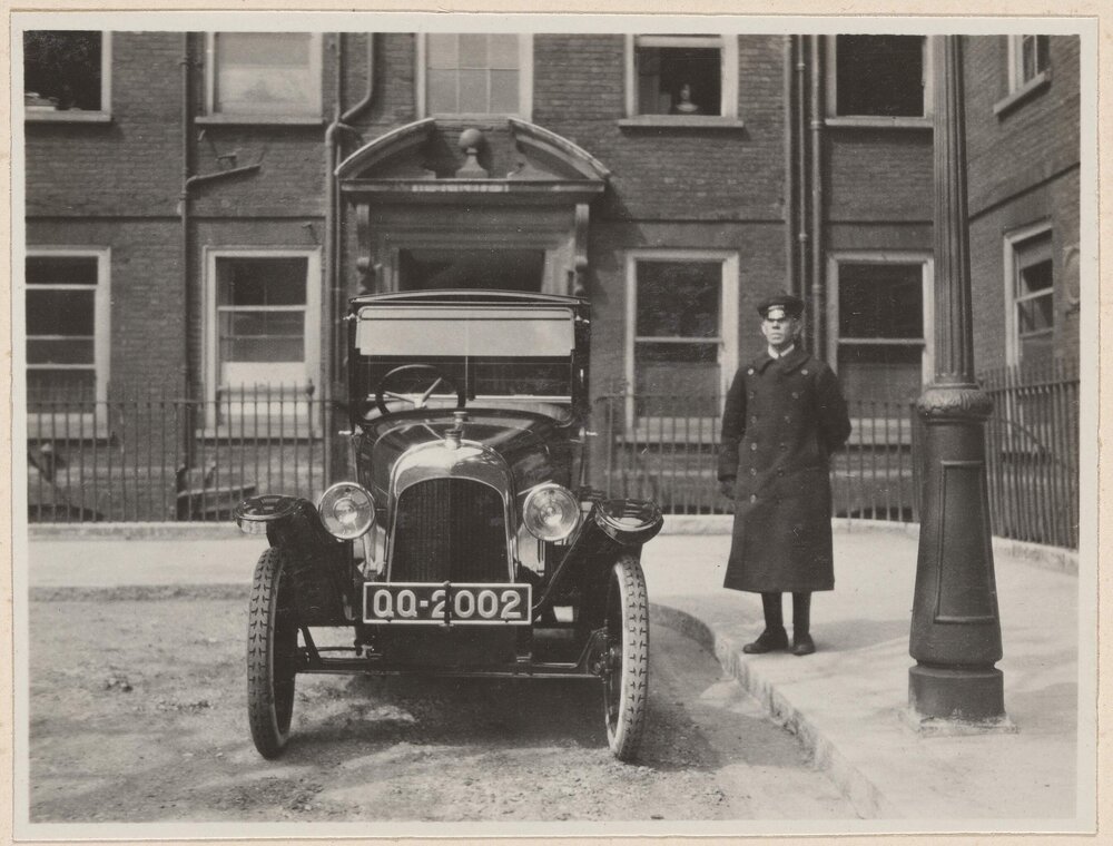 [Chauffeur standing next to Coup de Ville]