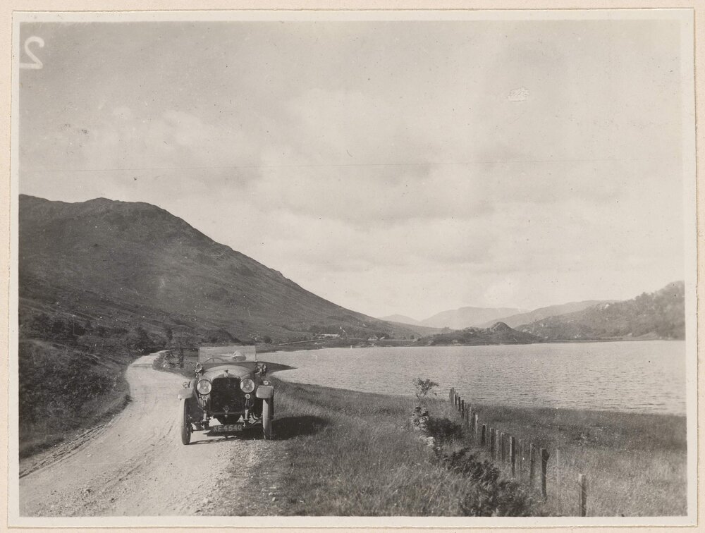 [Motor car on road beside lake]