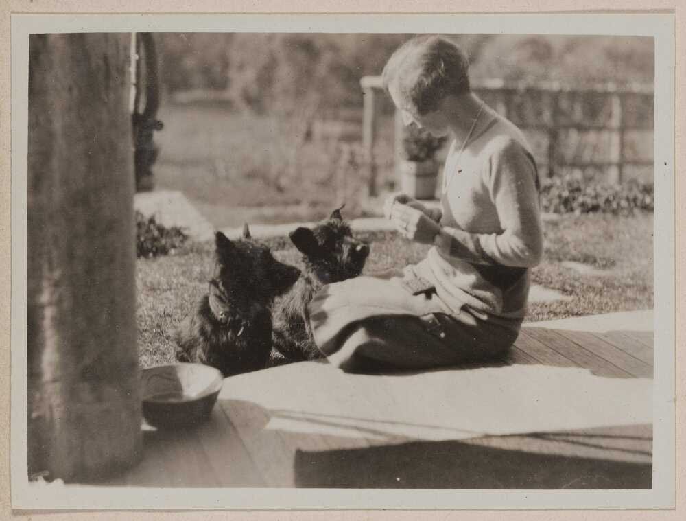 [Mabel feeding treats to her two dogs on back porch, Westerfield]