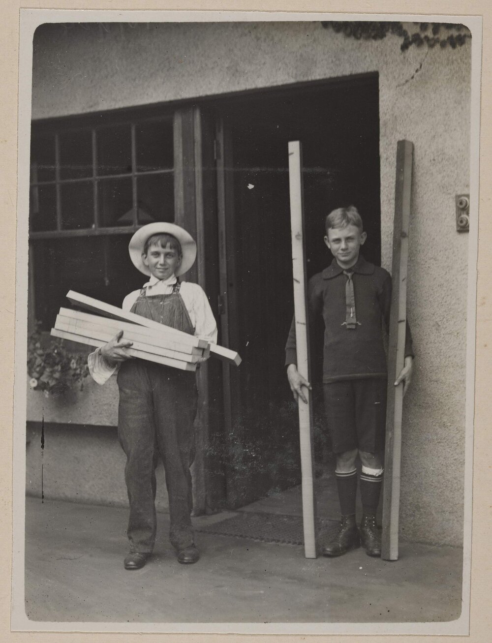 [Two young boys holding planks of wood]