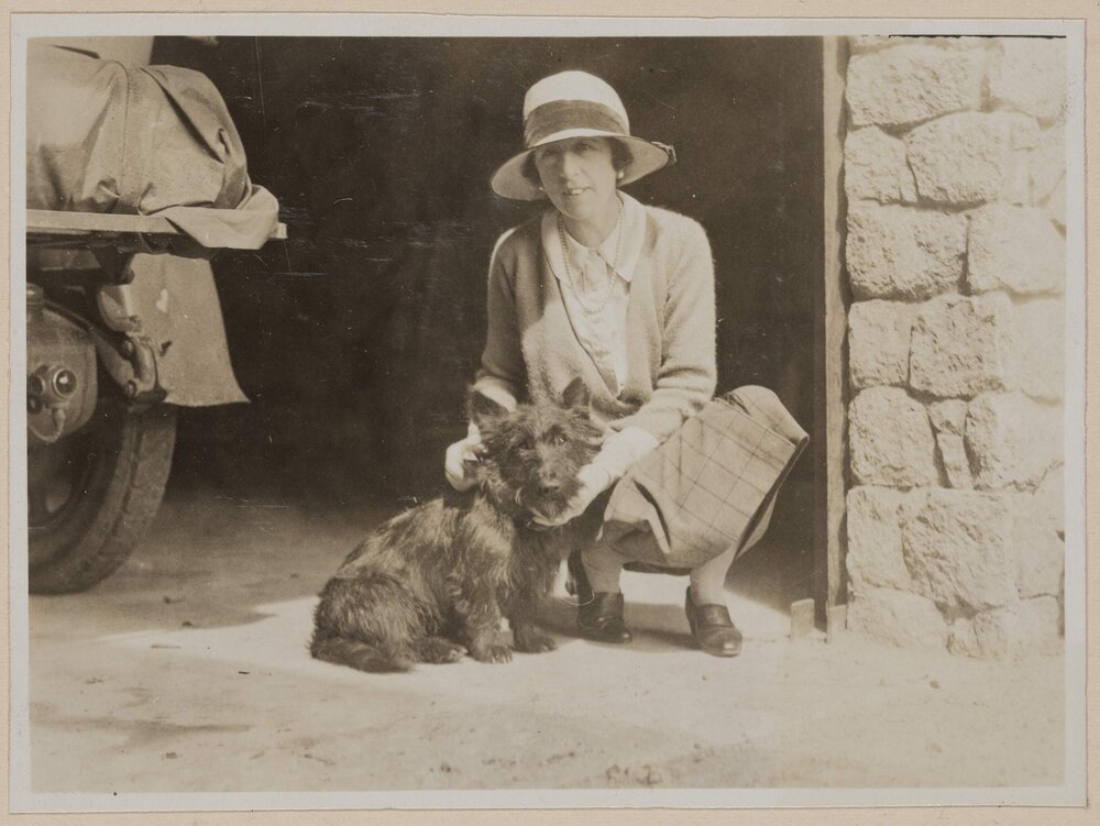 [Woman in crouched posed next to terrier dog]