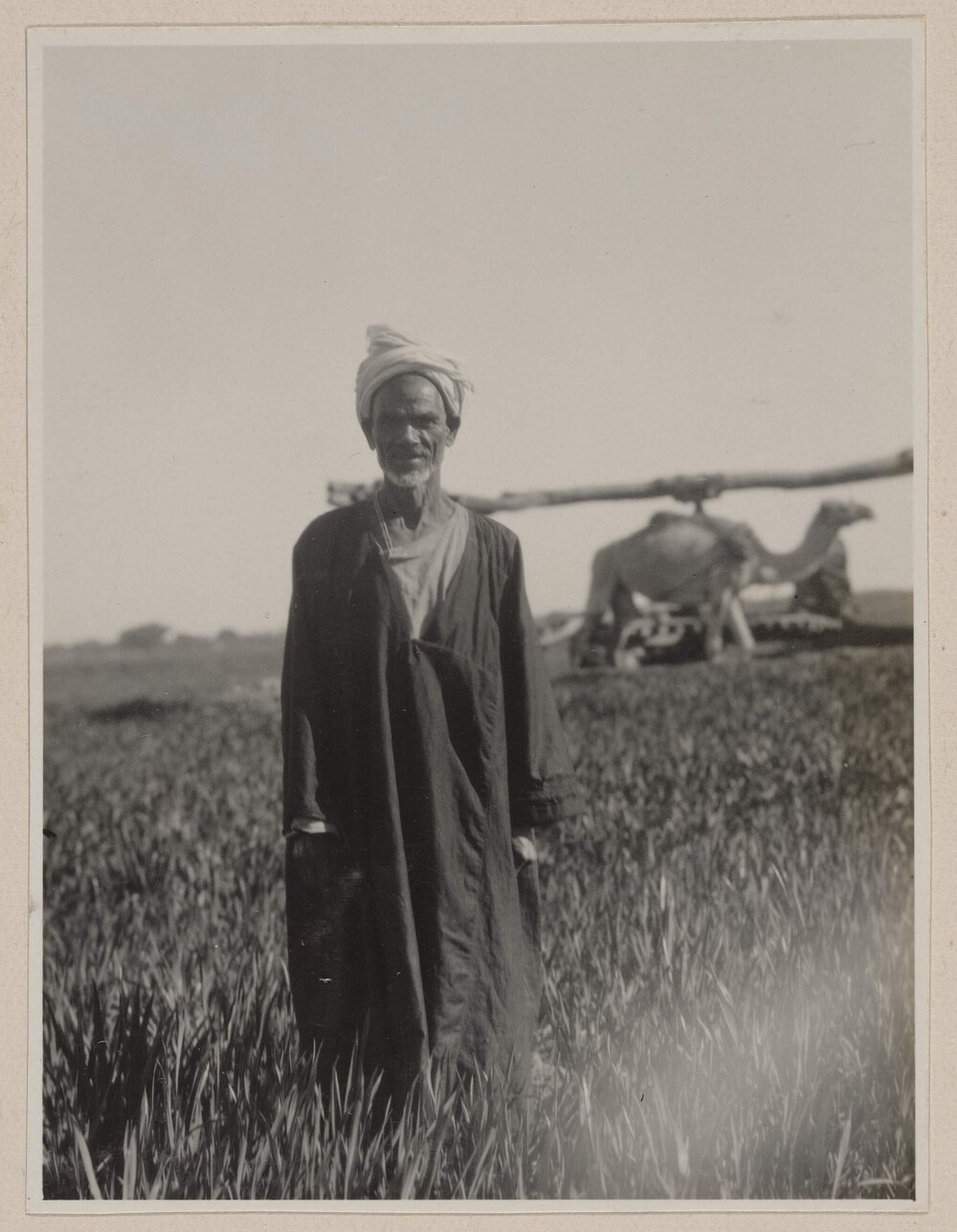 [Man in field wearing turban and long woollen cloak]